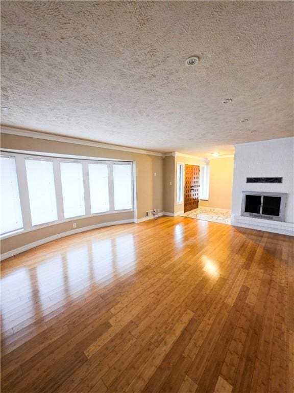 unfurnished living room with crown molding, light hardwood / wood-style flooring, and a textured ceiling