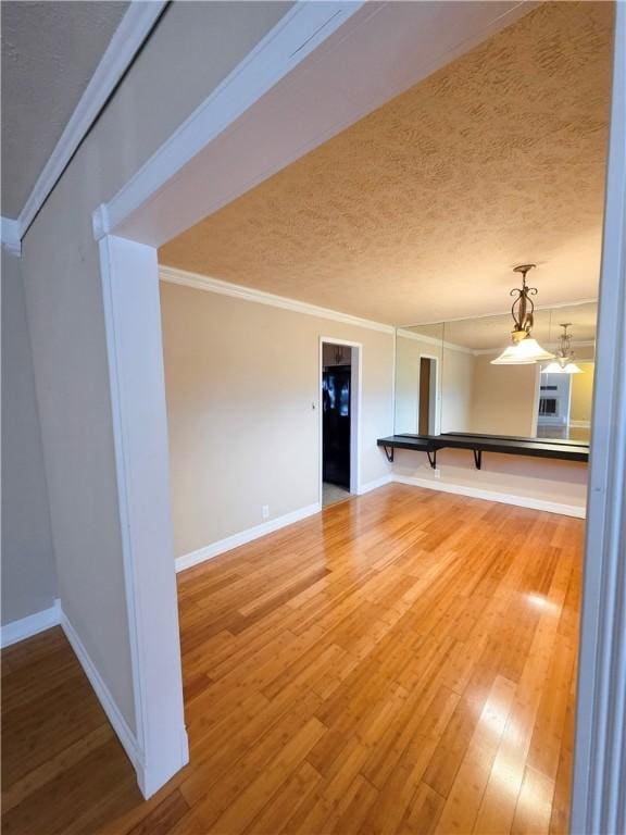 unfurnished room featuring wood-type flooring, ornamental molding, and a textured ceiling