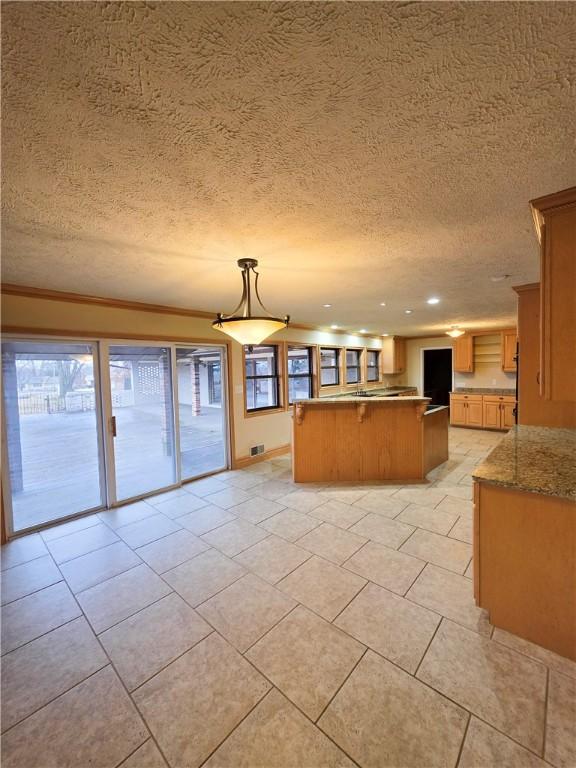 kitchen featuring hanging light fixtures, light stone counters, ornamental molding, a textured ceiling, and light tile patterned flooring