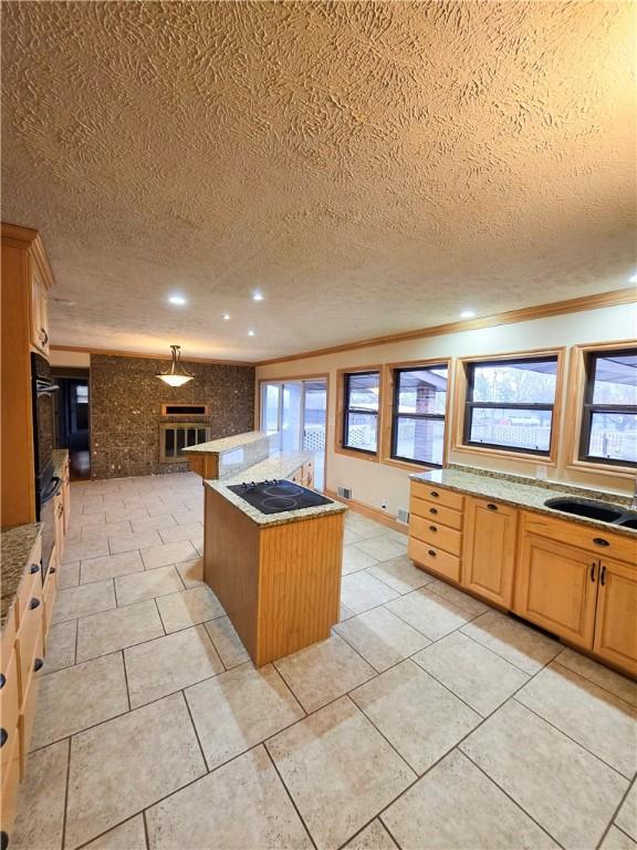 kitchen featuring sink, a center island, black appliances, ornamental molding, and a textured ceiling