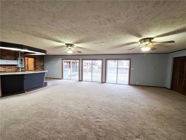 unfurnished living room with carpet floors, a textured ceiling, and ceiling fan