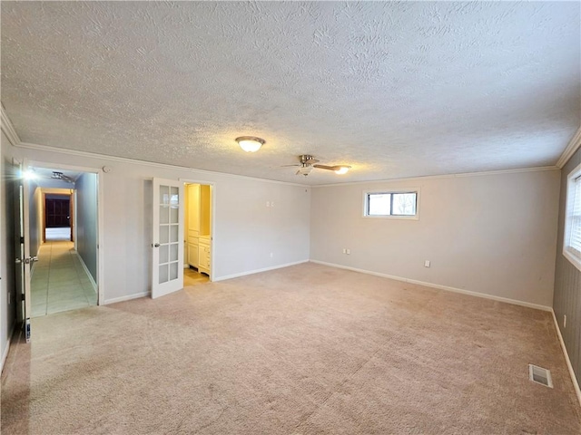 unfurnished room featuring ceiling fan, crown molding, light carpet, a textured ceiling, and french doors