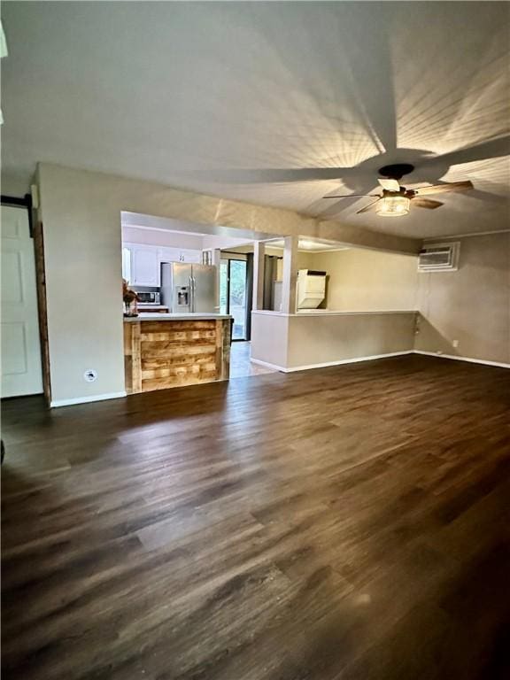 unfurnished living room featuring dark hardwood / wood-style floors, a wall unit AC, a barn door, and ceiling fan