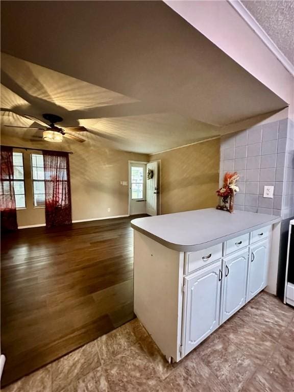 kitchen featuring ceiling fan, hardwood / wood-style floors, tasteful backsplash, white cabinets, and kitchen peninsula