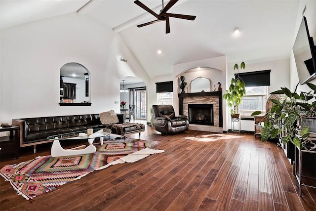 living room featuring ceiling fan, a fireplace, wood finished floors, visible vents, and beamed ceiling