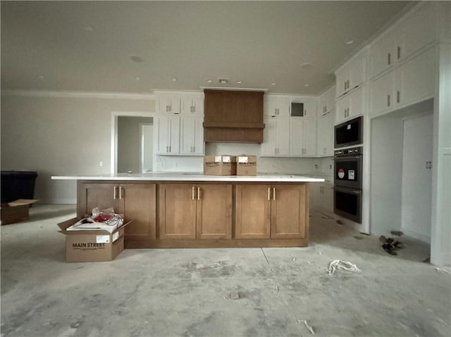 kitchen with white cabinetry, stainless steel double oven, custom range hood, and a spacious island