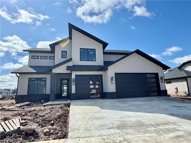 view of front of home with a garage, stucco siding, concrete driveway, and brick siding