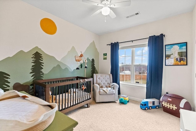 carpeted bedroom with a nursery area, baseboards, and a ceiling fan