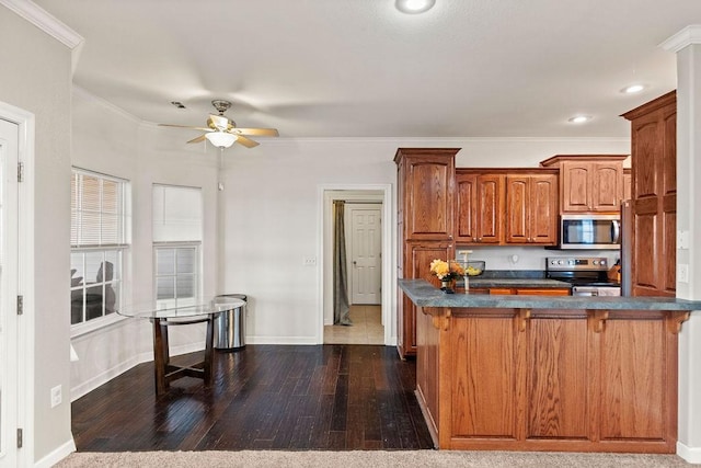 kitchen with appliances with stainless steel finishes, dark countertops, ceiling fan, a kitchen bar, and baseboards