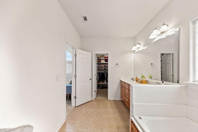 bathroom featuring vanity, a garden tub, tile patterned floors, a walk in closet, and baseboards