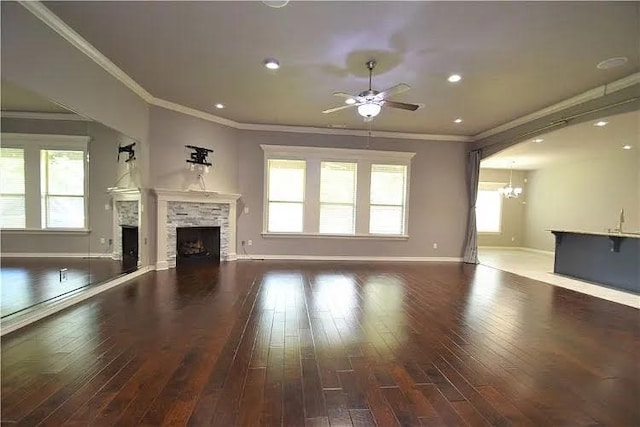 unfurnished living room featuring dark hardwood / wood-style flooring, crown molding, ceiling fan, and a fireplace