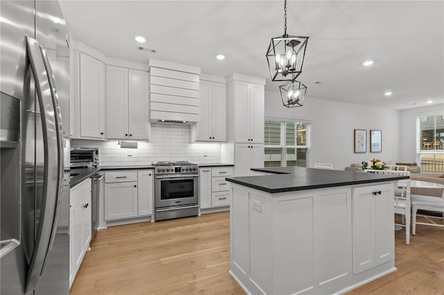 kitchen featuring white cabinetry, a center island, light hardwood / wood-style flooring, pendant lighting, and stainless steel appliances