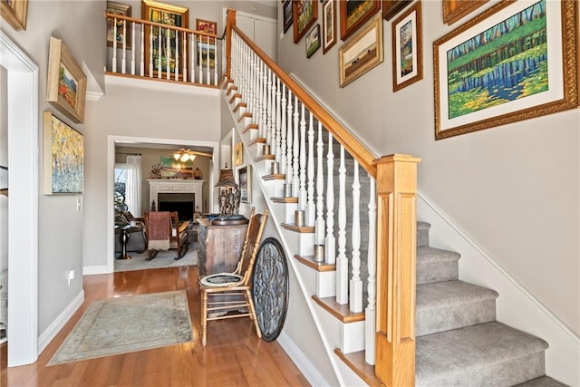 stairway featuring hardwood / wood-style floors, a towering ceiling, and ceiling fan