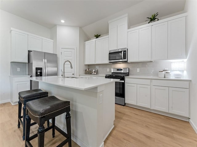 kitchen with white cabinetry, appliances with stainless steel finishes, a kitchen island with sink, and a breakfast bar area