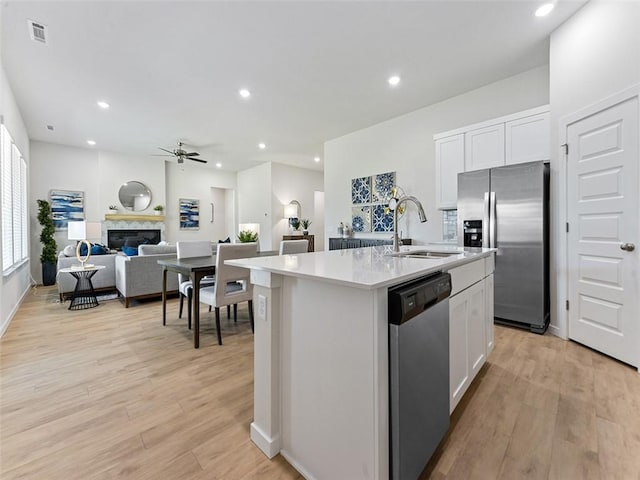 kitchen featuring sink, white cabinetry, appliances with stainless steel finishes, an island with sink, and light hardwood / wood-style floors