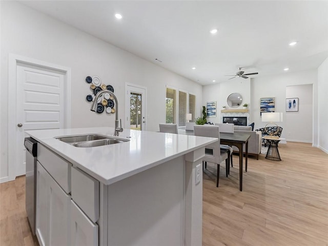 kitchen featuring sink, a center island with sink, stainless steel dishwasher, ceiling fan, and light hardwood / wood-style floors