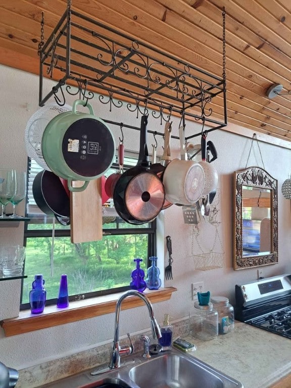 interior space with stainless steel stove, sink, and wooden ceiling