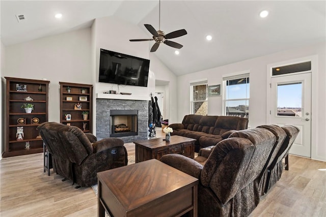 living room featuring ceiling fan, a fireplace, high vaulted ceiling, and light wood-type flooring