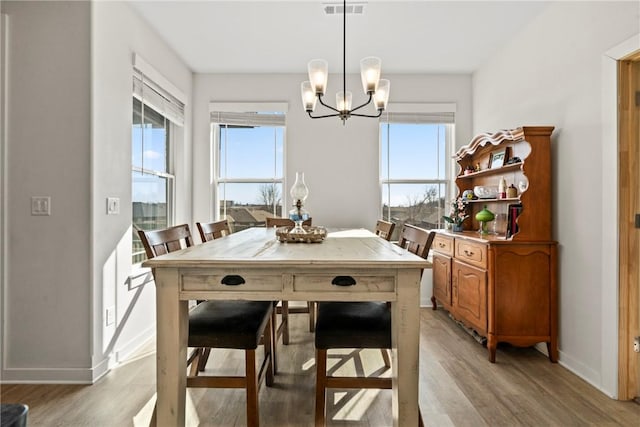 dining space featuring a healthy amount of sunlight, a chandelier, and light hardwood / wood-style floors