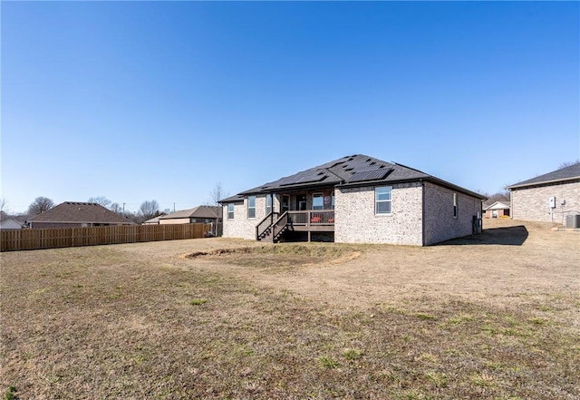 back of house featuring central AC unit, a lawn, and solar panels