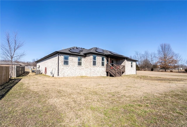 rear view of property with a yard, cooling unit, and solar panels