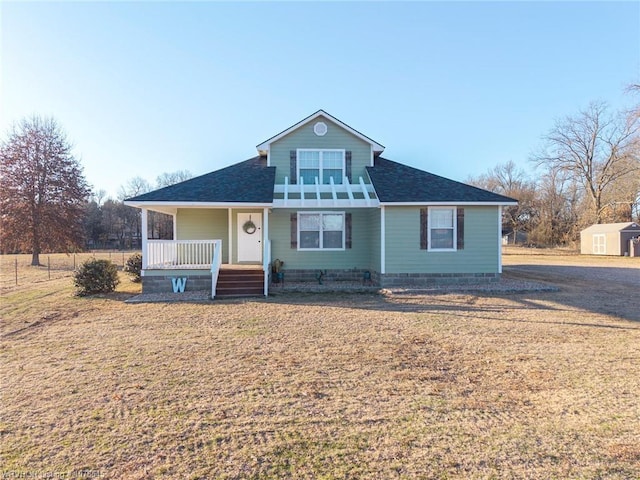 view of front facade featuring a porch, a front yard, and a shed