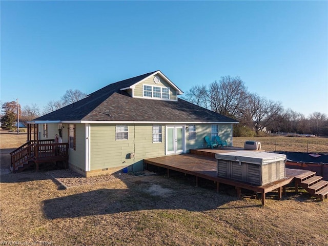 back of property with a hot tub and a deck