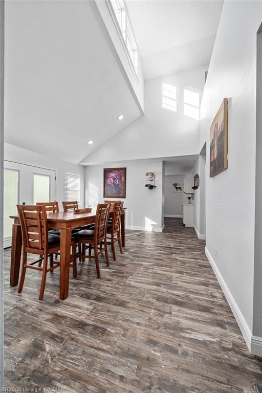 dining space featuring dark wood-type flooring, high vaulted ceiling, and french doors