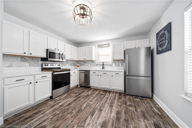 kitchen with appliances with stainless steel finishes, white cabinetry, sink, decorative backsplash, and dark wood-type flooring