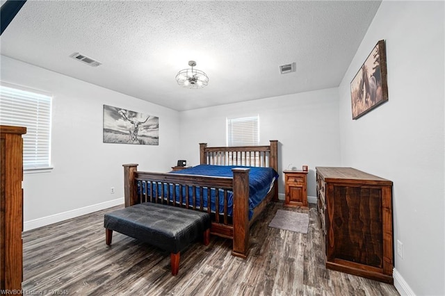 bedroom featuring dark wood-type flooring, a chandelier, and a textured ceiling