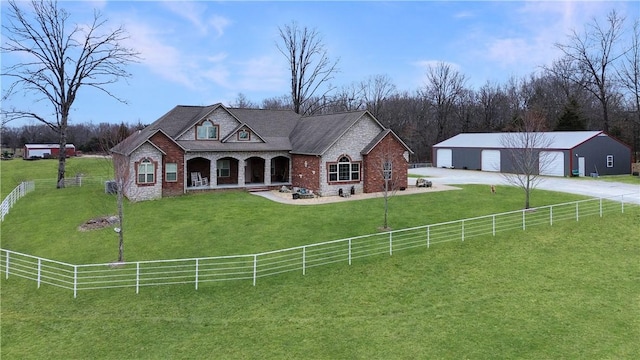 view of front of property featuring a garage, an outbuilding, a rural view, and a front lawn