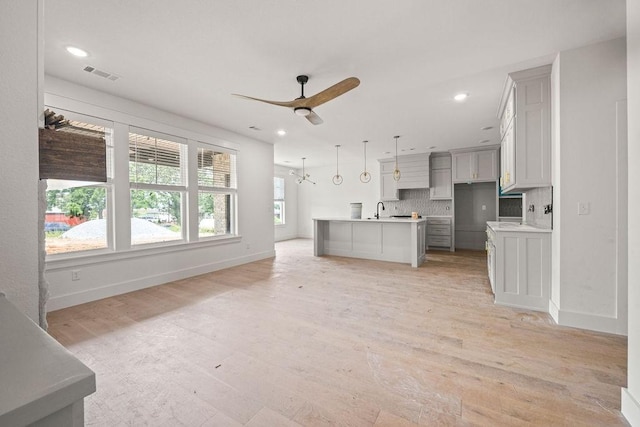 4750 Cowboy St, Springdale, AR 72762 - kitchen featuring light wood finished floors, open floor plan, ceiling fan, backsplash, and light countertops