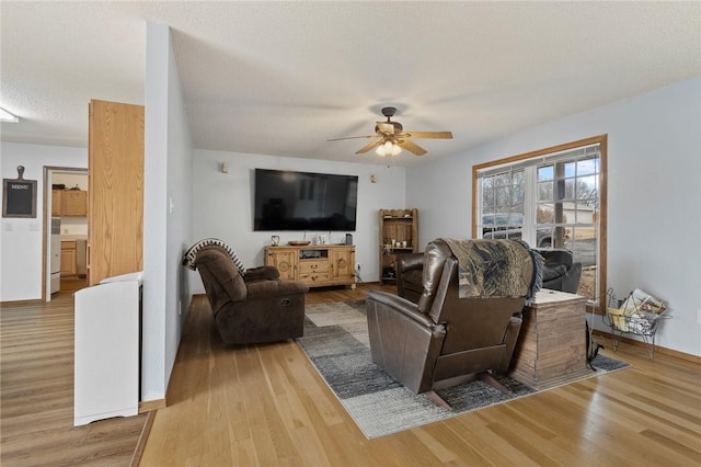 living room with ceiling fan, light hardwood / wood-style flooring, and a textured ceiling