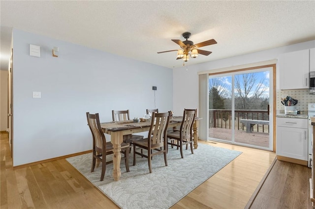 dining room with ceiling fan, light hardwood / wood-style flooring, and a textured ceiling