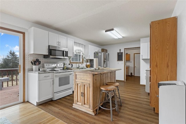 kitchen with white cabinetry, a kitchen island, wood-type flooring, and appliances with stainless steel finishes