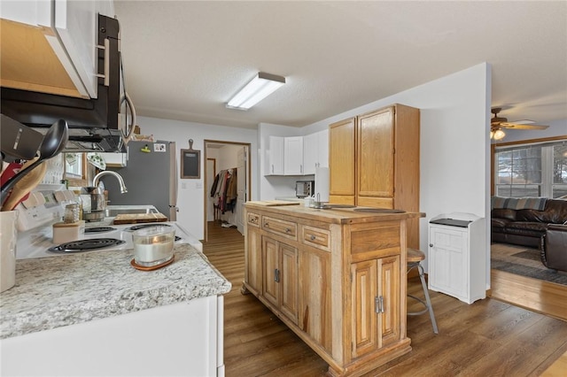 kitchen featuring stainless steel refrigerator, white cabinets, hardwood / wood-style flooring, a center island, and ceiling fan