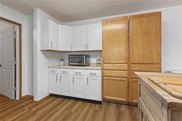 kitchen featuring white cabinetry, wood-type flooring, butcher block counters, and a textured ceiling