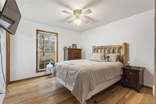 bedroom with ceiling fan, light hardwood / wood-style flooring, and a textured ceiling