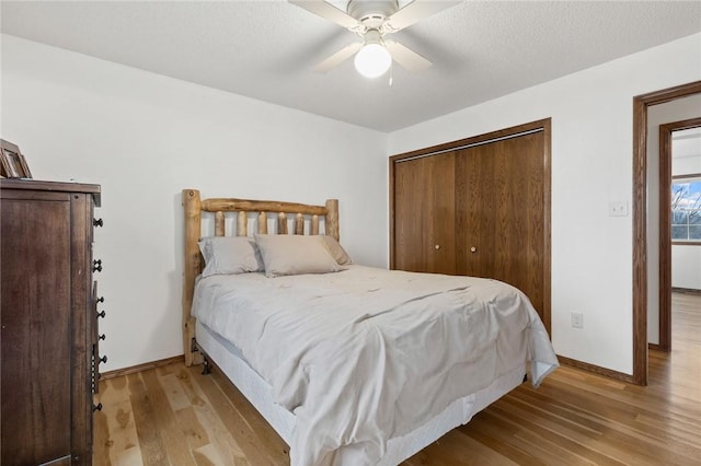 bedroom featuring ceiling fan, a textured ceiling, light wood-type flooring, and a closet