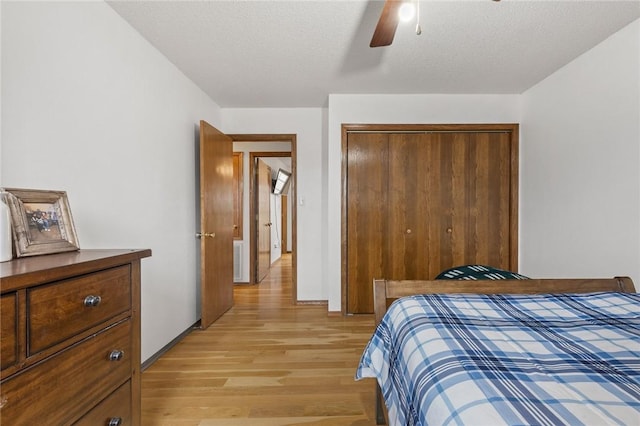 bedroom with ceiling fan, a textured ceiling, light hardwood / wood-style floors, and a closet