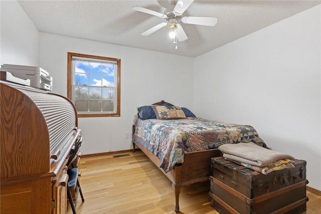 bedroom featuring ceiling fan, light hardwood / wood-style floors, and a textured ceiling