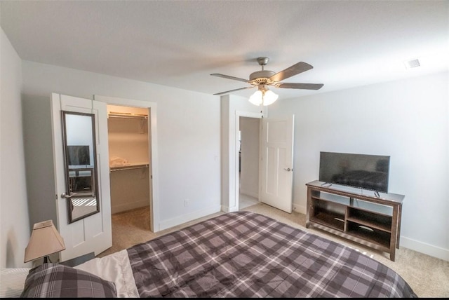 bedroom featuring ceiling fan, light colored carpet, a spacious closet, and a closet