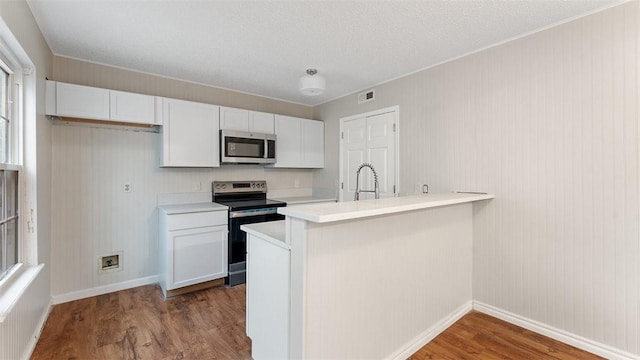 kitchen featuring appliances with stainless steel finishes, white cabinets, light hardwood / wood-style floors, and kitchen peninsula