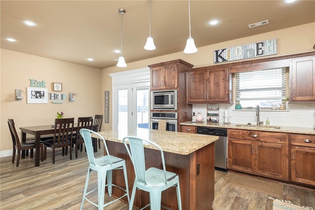 kitchen featuring sink, tasteful backsplash, a center island, appliances with stainless steel finishes, and pendant lighting