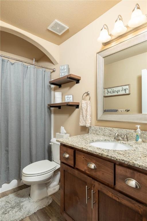 bathroom with hardwood / wood-style flooring, vanity, toilet, and walk in shower