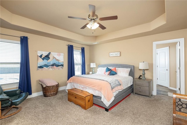 bedroom with a raised ceiling, carpet flooring, and ceiling fan