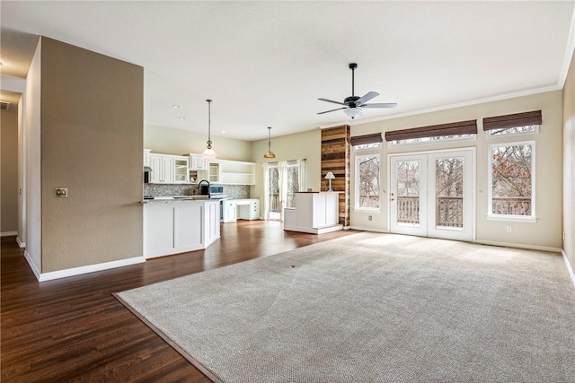 unfurnished living room with ceiling fan, baseboards, and dark wood-type flooring