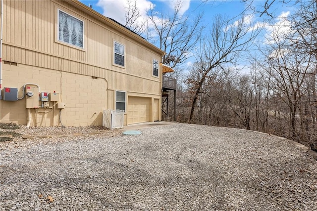 view of side of property with an attached garage and gravel driveway