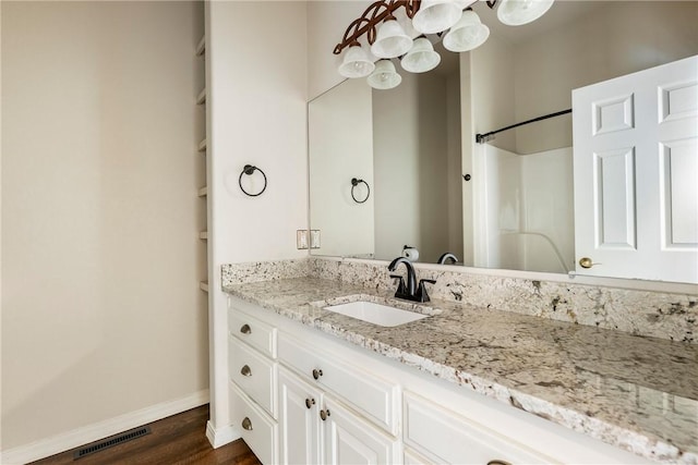 bathroom with baseboards, visible vents, a shower, wood finished floors, and vanity