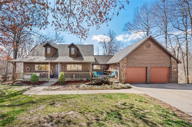 view of front of home featuring a shingled roof, covered porch, a garage, driveway, and a front lawn